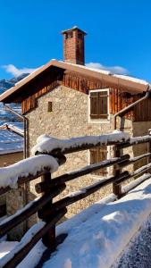 ein Blockhaus im Schnee mit einem Zaun in der Unterkunft Baita natura a portata di mano! in Frabosa Soprana
