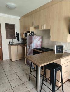 a kitchen with wooden cabinets and a counter top at Grace209 Bains Lodge in Bloemfontein