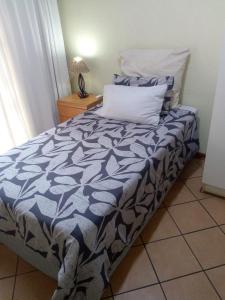 a bed with a blue and white comforter in a room at VILLA LA CORRIE Guest Lodge in Steelpoort