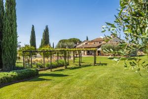 a garden with a pergola and trees and a house at Il casale degli olivi in Capalbio