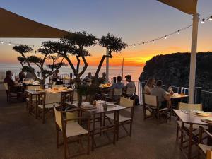 a group of people sitting at tables with a view of the ocean at Club Menorca - Solo Adultos in Cala'n Porter