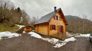 a small wooden cabin with a deck in the snow at Chalet Ô Mont Dore in Le Mont-Dore
