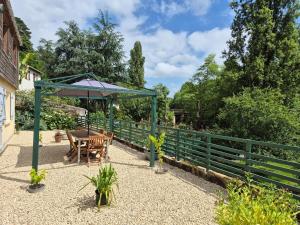 a patio with a table and an umbrella at Le Pont Bas bord de rivière proche Puy du Fou in Mortagne-sur-Sèvre +21 photos