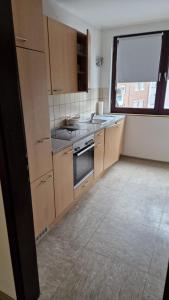 a kitchen with wooden cabinets and a large window at Zimmer F in Mönchengladbach +6 photos