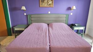 a bedroom with a pink bed with two tables at Arte Annapolis Inn in Rhodes Town