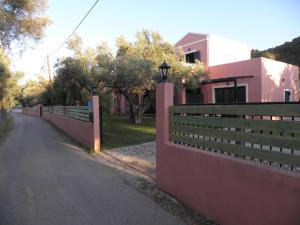 a fence next to a road next to a pink house at Ionian Breeze Studios in Lefkada