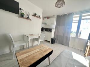 Una sala de estar con una mesa y una cocina. en Cabane au Bord du Lac - Les Jardins de Vandré - Parc Jeux Tennis Spa Nature - IDEAL FAMILLE, en Vandré