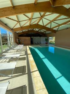 an indoor swimming pool with a wooden ceiling at Résidence de Nodeven in Guissény