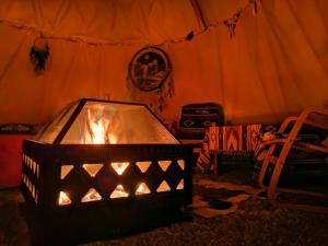 a fireplace in a room with a tent at Teepee Camp Lounky in Chodouny