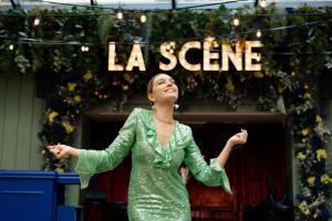 a woman in a green dress standing in front of a sign at Chouchou Hotel in Paris