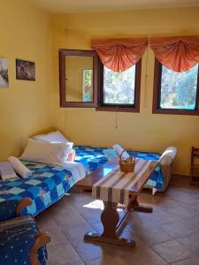 ein Zimmer mit zwei Betten und einem Tisch und Fenstern in der Unterkunft Bill's Garden Villa in Kalamos