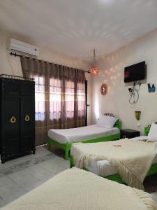 a hotel room with two beds and a tv at Hôtel Ayachi in Tunis