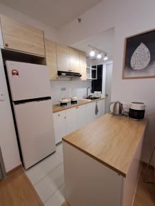 a kitchen with a white refrigerator and a wooden counter at MayaBay Residence Splash Mania Gamuda Cove Homestay by Ara in Pulau Kempas