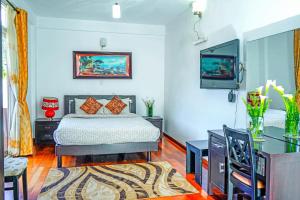 a bedroom with a bed and a flat screen tv at Mountain Breeze Chill Apartment in Nuwara Eliya