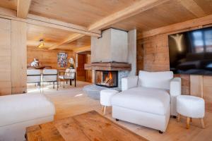 Una sala de estar con muebles blancos y chimenea. en Panoramic 5 Bedroom Luxury Chalet with Butler, en Château-d'Oex