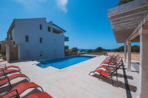 a row of chairs sitting next to a swimming pool at Penthouse SKY DELUXE in Novalja