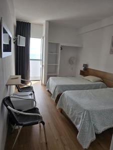 a hotel room with two beds and a desk and a chair at AL Moniz in Machico