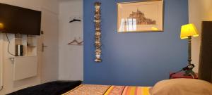 a bedroom with a blue wall with a picture on the wall at Le jardin bernard PERRIER in Montbazin