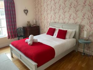 a bed with a teddy bear sitting on a red blanket at Pass the Keys Superbly Located Handsome Georgian Townhouse in Shrewsbury