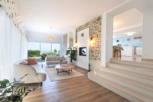 ein Wohnzimmer mit Sofa und Tisch in der Unterkunft Manava Villa vue mer et Mont Saint Michel piscine intérieure in Saint-Jean-le-Thomas