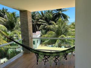 a balcony with a hammock and palm trees at Casa Itacimirim in Camacari