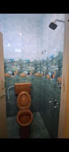 a bathroom with a toilet with a painting on the wall at Subramanya Inn in Tiruchchendūr