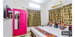 Un dormitorio con una puerta rosa y una cama en saltlake inn, en kolkata