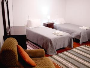 a hotel room with two beds and a chair and a chair at Green Valley Cruzinhas House with Fireplace & BBQ in Santana
