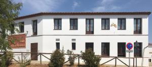 a white building with black windows on a street at Casa Asador Sierra De Aracena in Aracena