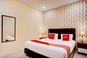 a bedroom with a bed with red pillows and a mirror at Hotel O Medan City Near Sun Plaza Formerly Residence Anugrah in Medan +84 photos