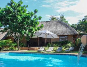 a resort with a swimming pool and an umbrella at AmaZulu Lodge in St Lucia