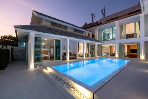 une maison avec une grande piscine en face dans l'établissement White Pool Villa Chiangmai, à Chiang Mai