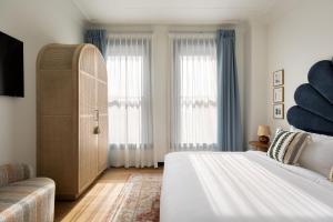 a bedroom with a bed and a dresser and two windows at Granger Hotel San Diego Downtown Gaslamp Quarter, a Member of Design Hotels in San Diego