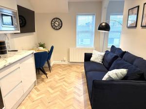 a living room with a blue couch and a kitchen at The Loft Apartments Cardiff Central in Cardiff