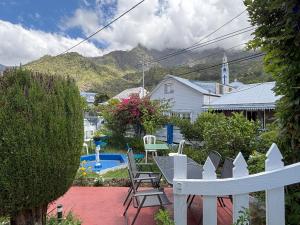 a backyard with a white fence and a table and chairs at Chambre gite d'étape les Carillons in Cilaos