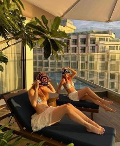 Dos mujeres en bikini sentadas en sillas en un balcón en Mũi Né Resort - Mandala Mer, en Mui Ne
