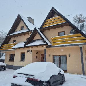 a snow covered house with a car in front of it at Hubert in Białka Tatrzanska