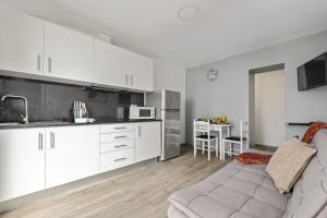 a kitchen with white cabinets and a couch in a room at Seaside Charm II in Câmara de Lobos