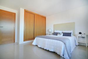 biała sypialnia z dużym łóżkiem i drewnianą szafką w obiekcie Apartamento con terraza con vistas al mar w mieście Villanueva de Arosa