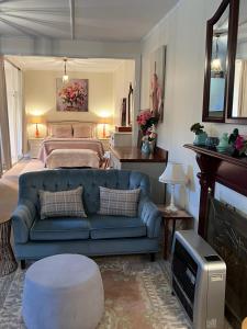 ein Wohnzimmer mit einer blauen Couch und einem Bett in der Unterkunft Katoomba Cosy Cottage- entire 65sqm cottage in Katoomba