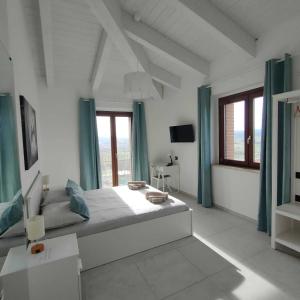 a white bedroom with a large bed with blue curtains at Agriturismo Giorgini in Marsciano +18 photos
