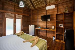 Schlafzimmer mit Holzwänden, einem Bett und einem TV in der Unterkunft Gecko Villa & Bungalows in Nusa Lembongan