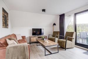 a living room with a couch and chairs and a tv at Rietzanger I Cottage met Mooie Inrichting in Zwiggelte