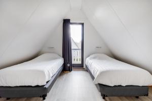 two beds in a room with white walls and a window at Rietzanger I Cottage met Mooie Inrichting in Zwiggelte +48 photos