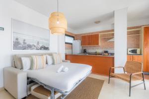a bedroom with a white bed and a kitchen at Apartamentos Moon Dreams Puerto in El Puerto de Santa María
