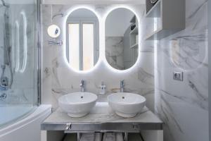 a white bathroom with two sinks and a mirror at Cesare ai Cavalieri Suites in Rome