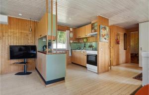 a kitchen with wooden cabinets and a flat screen tv at 2 Bedroom Nice Home In Jægerspris in Jægerspris