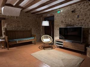 a living room with a flat screen tv and a chair at El Molí Nou - Rural flats in Peñarroya de Tastavins