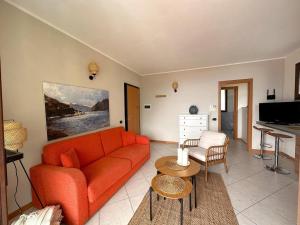 a living room with an orange couch and a table at Like Heaven Argegno Pool & Lake View in Argegno