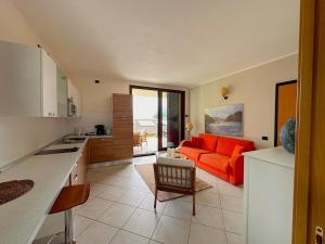 a kitchen and a living room with an orange couch at Like Heaven Argegno Pool & Lake View in Argegno